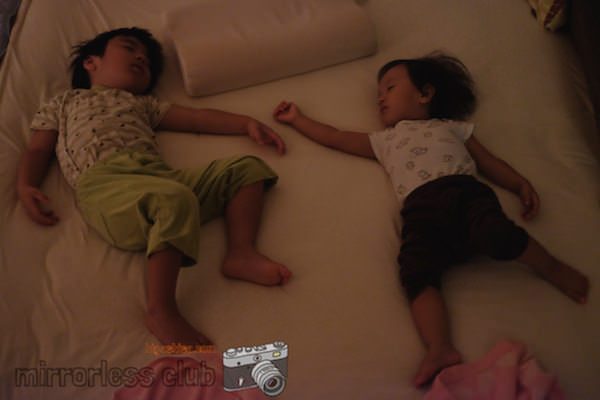 xt10.jpg: 寝ている2人の子供がベッドに横たわっている写真。